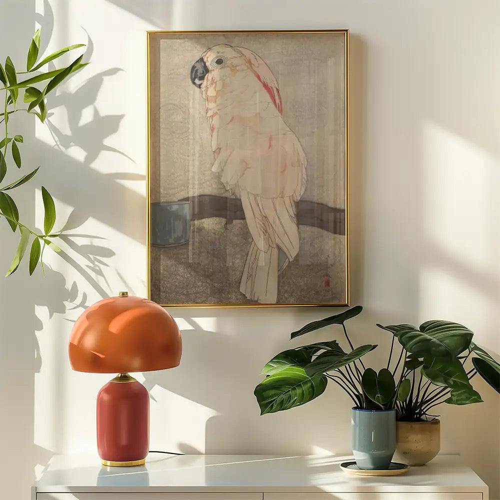 Painting of a parrot in a gold frame hanging on a wall beside a modern lamp and potted plants.