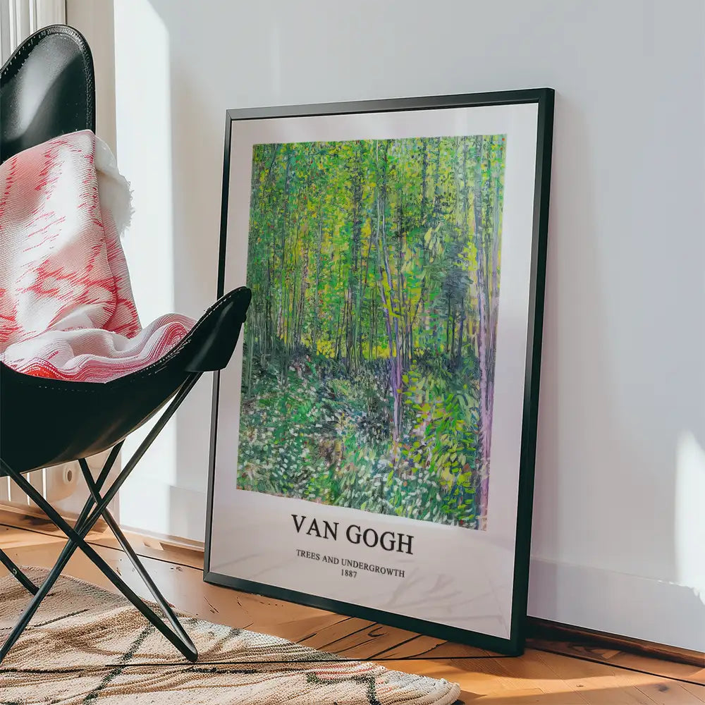 Framed poster of Van Gogh's "Trees and Undergrowth" (1887) displayed next to a black chair and blanket.