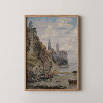 Framed painting of a coastal landscape featuring a rocky shoreline, charming towers, and a serene sky.
