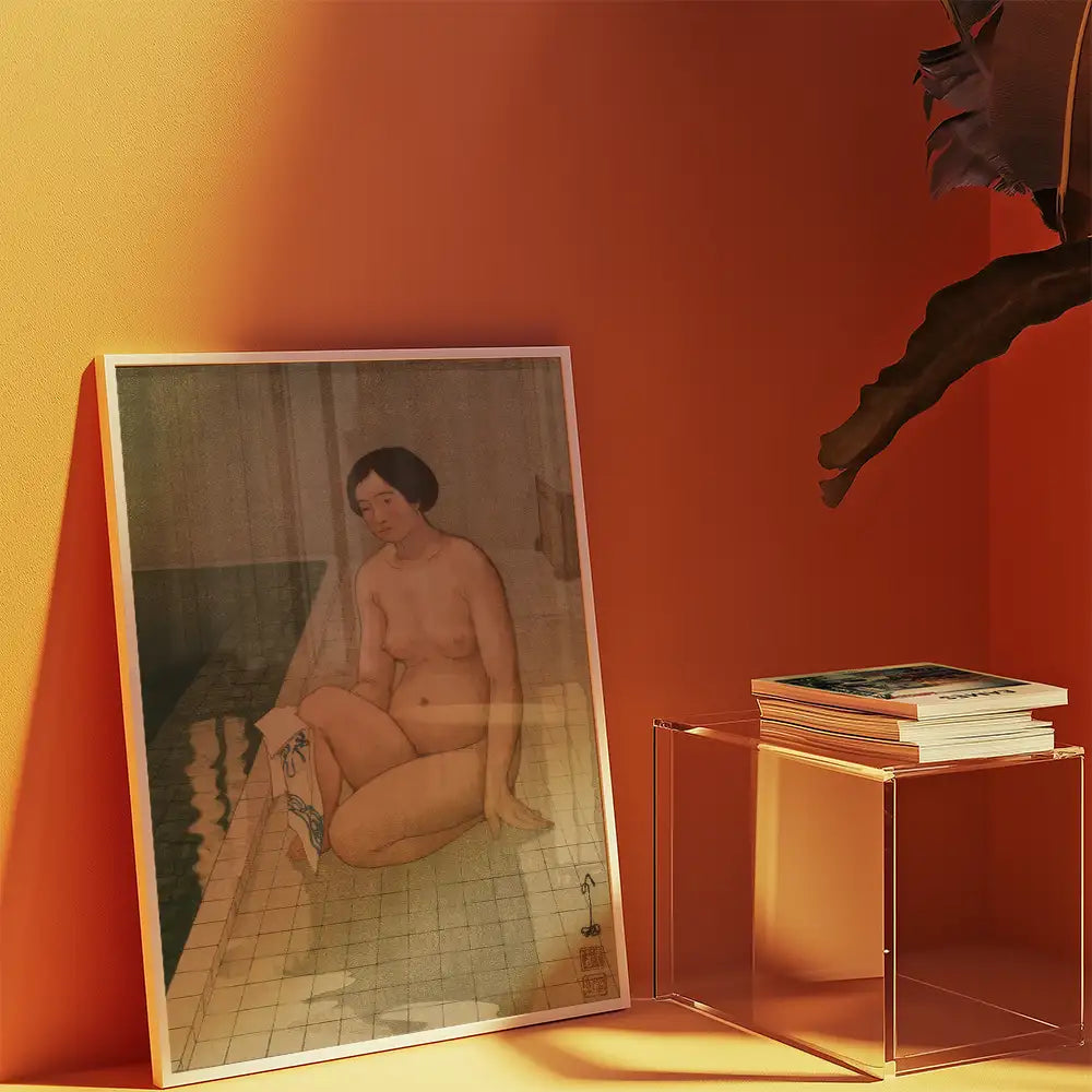 Artistic painting of a nude woman seated by a pool, framed and displayed against an orange wall, next to a clear acrylic table with stacked books.