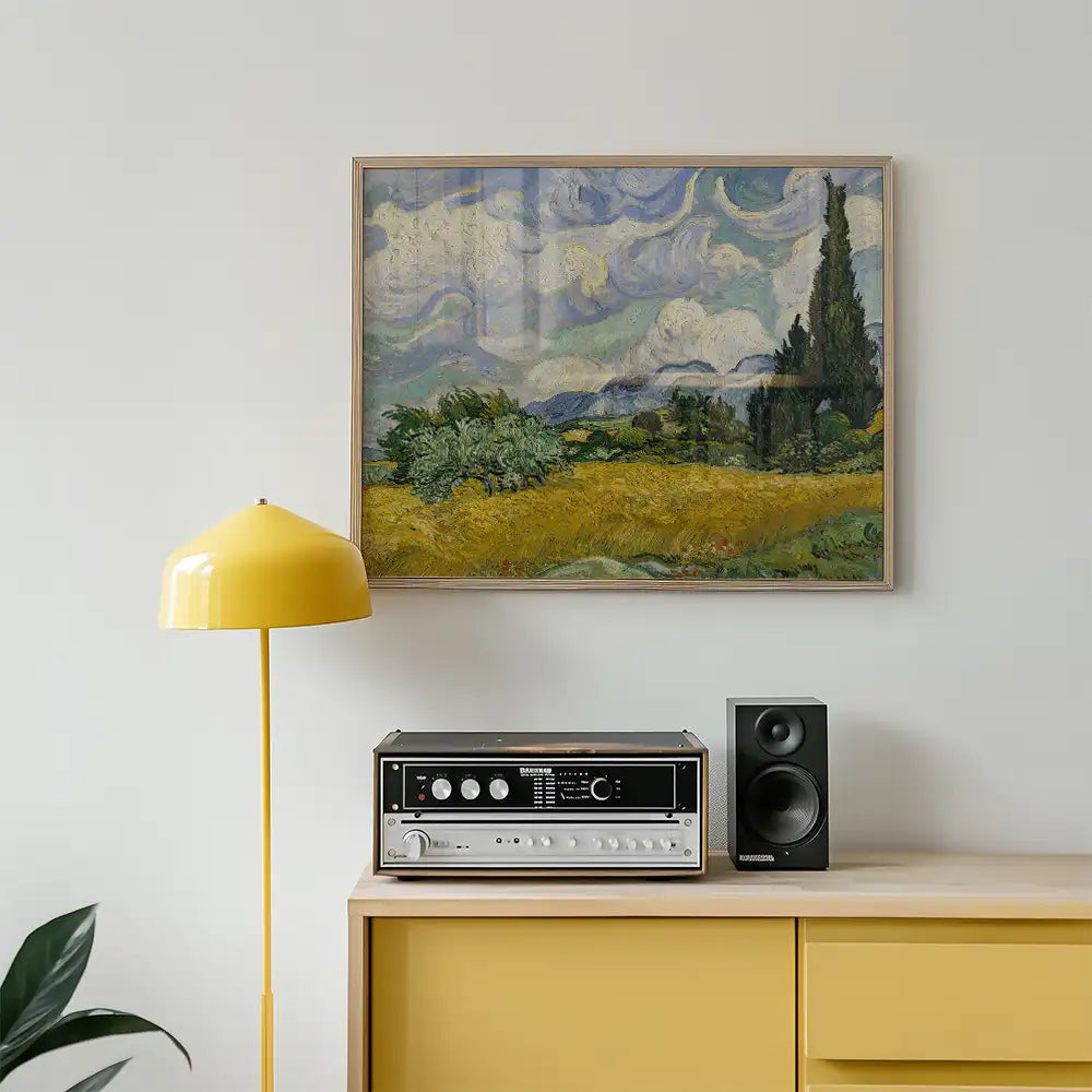 Painting of a vibrant landscape with fields and trees displayed above a mid-century modern console with a yellow lamp and speakers.