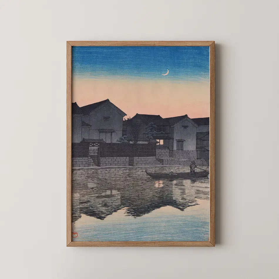 Framed painting of a serene landscape featuring traditional houses along a river at dusk, reflecting the pale blue sky and crescent moon.