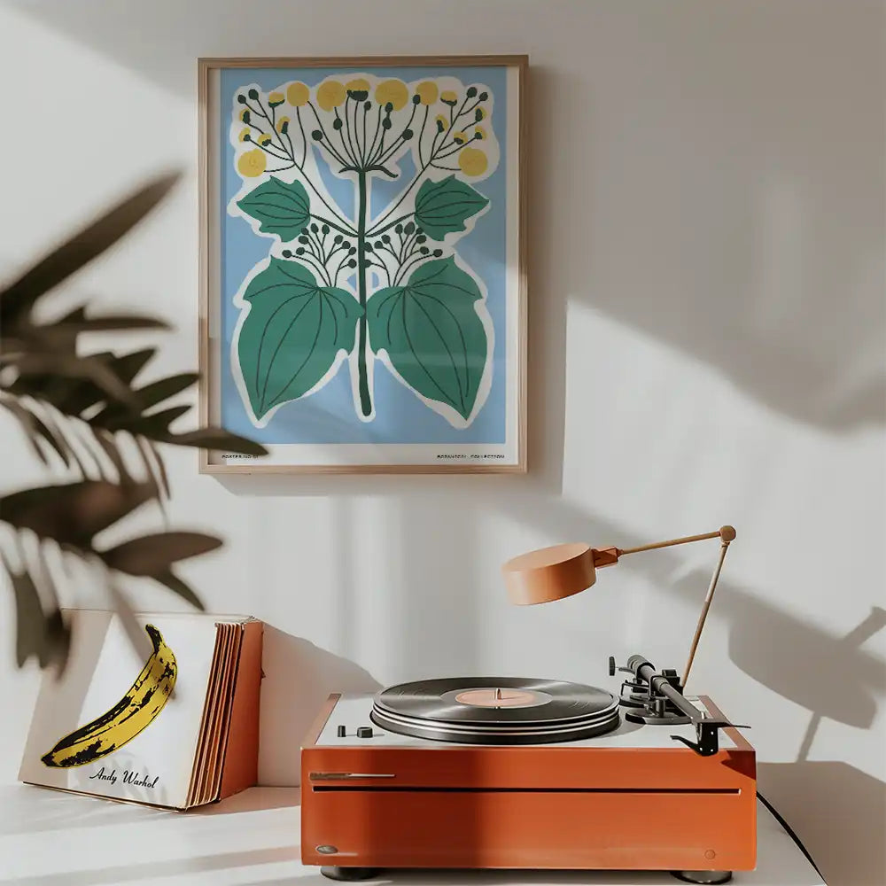 Modern botanical art print featuring vibrant yellow flowers and green leaves against a blue background, displayed in a stylish interior with a record player.