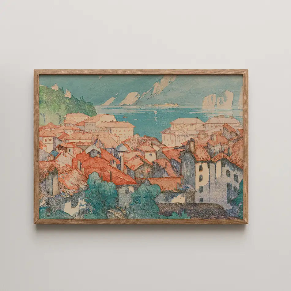 Colorful painting of a coastal town with red-tiled roofs, trees, and a serene blue sea in the background, framed in light wood.