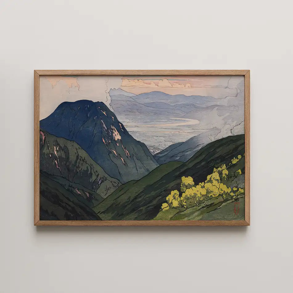 Framed landscape painting featuring mountains and a valley with lush green hills and yellow flowers under a cloudy sky.