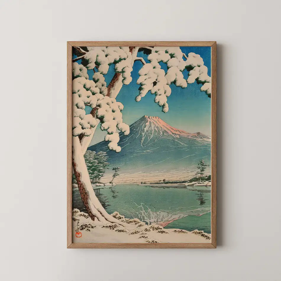 Framed painting of a snow-covered landscape featuring a mountain and lake, with white trees in the foreground and a blue sky.