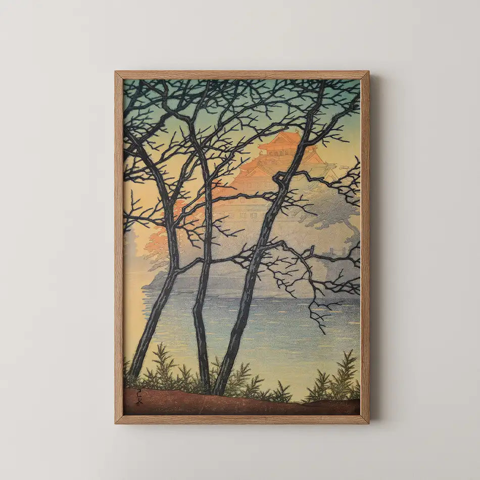Framed painting of a serene landscape with silhouetted trees and a colorful sunset reflecting on a lake.