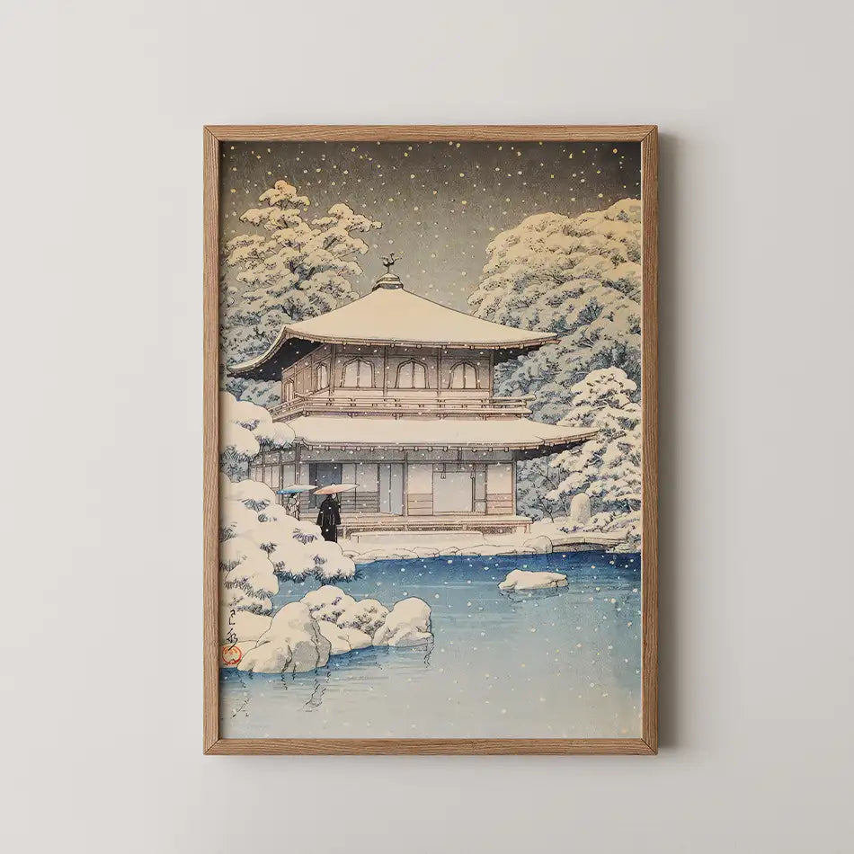 Framed painting of a snow-covered traditional Japanese building surrounded by trees and a serene pond
