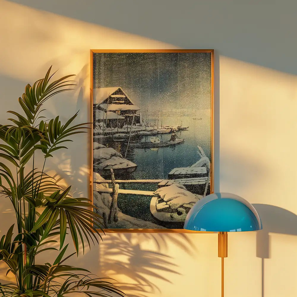 Framed painting of a snowy marina scene with boats, displayed on a wall beside a plant and a modern lamp.