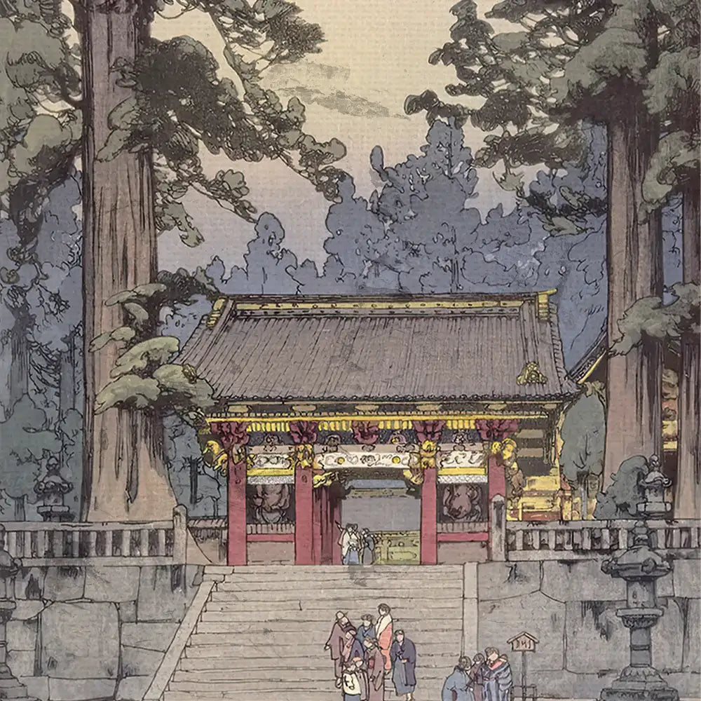 Japanese temple entrance surrounded by tall trees, featuring ornate red and gold details, with visitors walking up the stone steps.