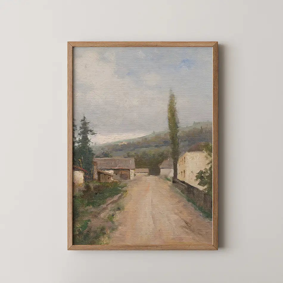 Landscape painting featuring a dirt road surrounded by trees and buildings, framed in wood.
