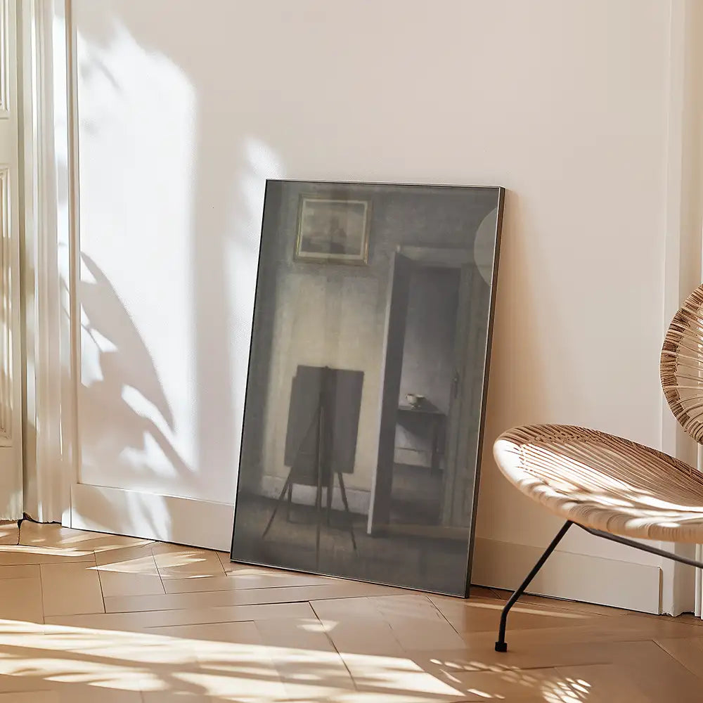 Framed painting leaning against a wall in a sunlit room, with a wooden chair nearby.