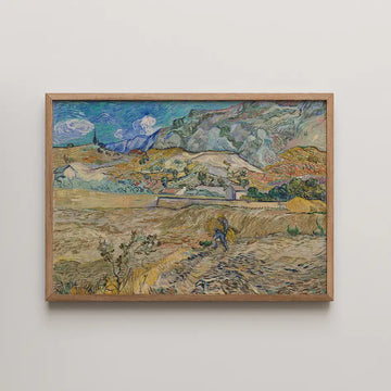 Framed painting of a scenic landscape featuring hills, a blue sky with clouds, and a figure working in a field.