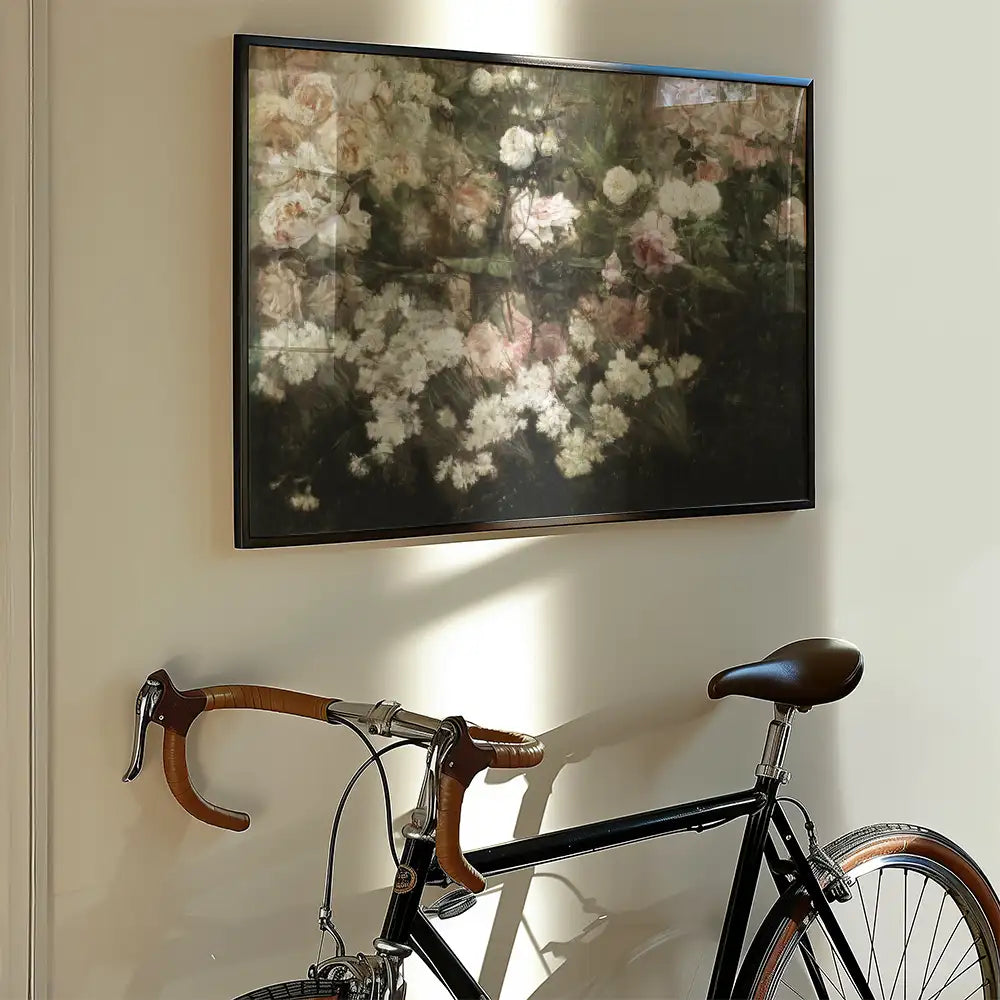 Framed floral painting hanging on a wall next to a vintage bicycle.