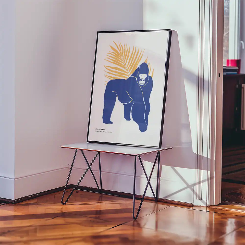 Modern art poster featuring a stylized blue gorilla with a yellow leaf background, displayed on a minimalist table in a contemporary setting.