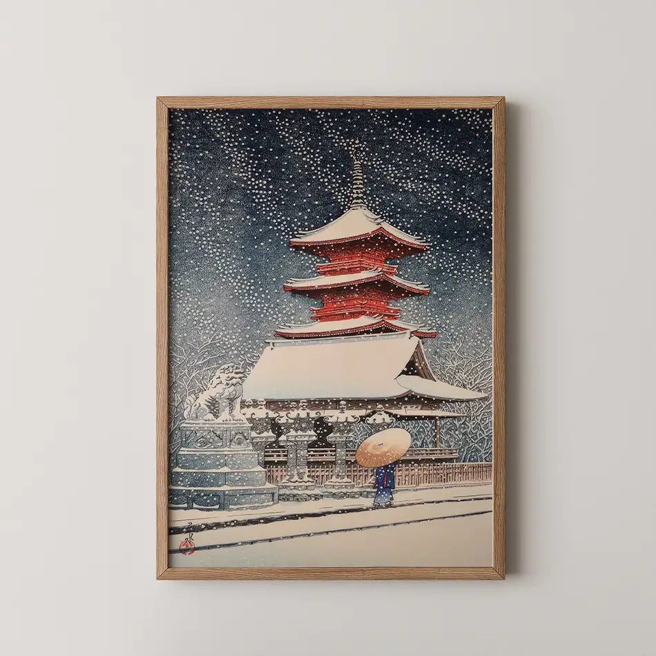 Framed painting of a traditional Japanese pagoda in the snow, with a figure carrying an umbrella in the foreground.