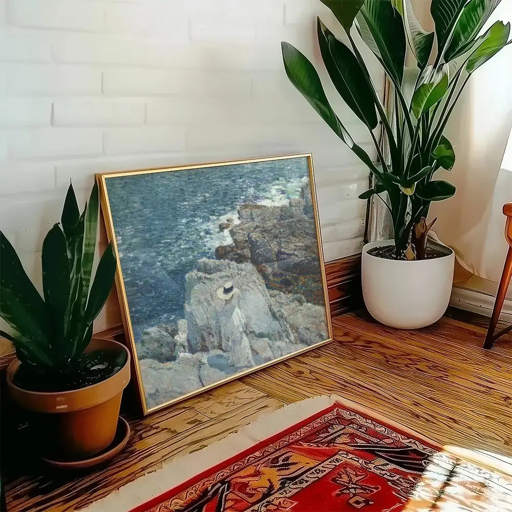 Painting of a coastal scene featuring rocks and water, displayed in a stylish interior setting with plants and warm wood accents.