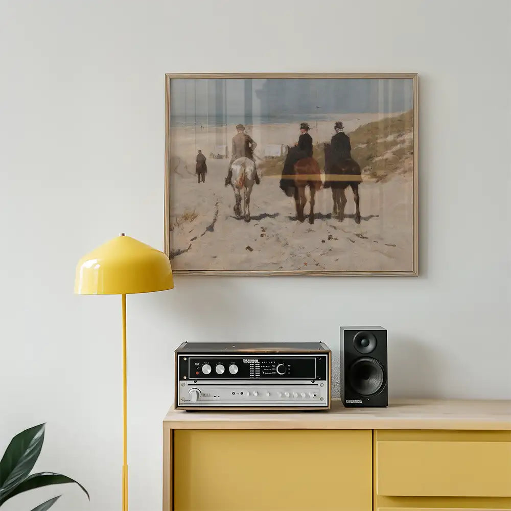Framed painting of three figures on horseback walking along a beach, displayed above a yellow lamp and retro audio equipment on a wooden sideboard.
