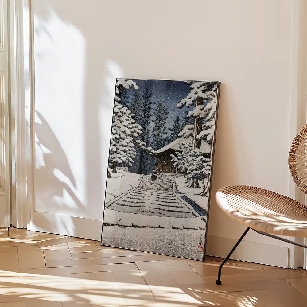 Painting of a snow-covered landscape with a cabin and trees, leaning against a wall in a well-lit interior space.