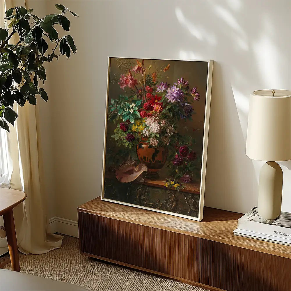 A vibrant painting of a floral arrangement in a decorative vase, framed and displayed on a wooden surface beside a lamp and plant.
