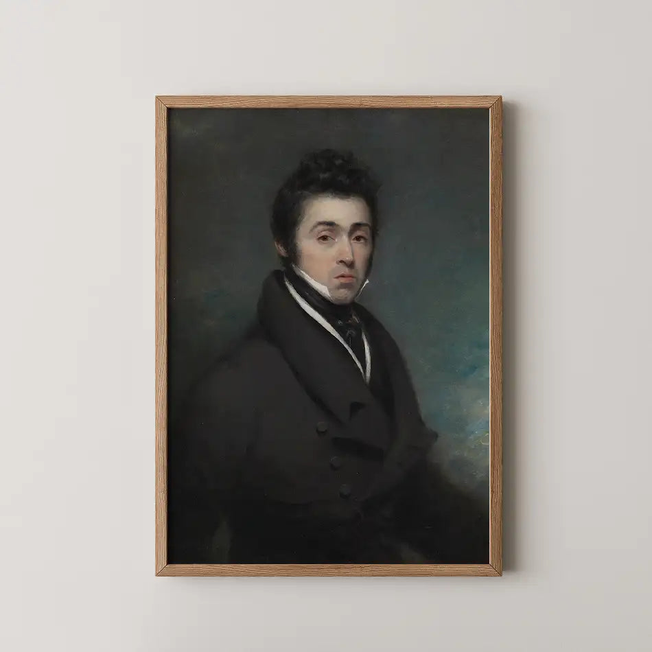 Portrait of a young man in a dark coat, set in a wooden frame against a neutral wall background.