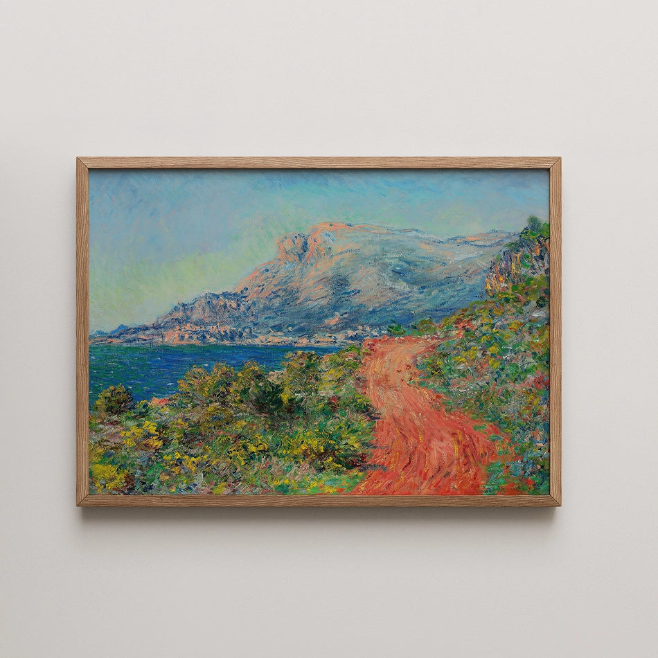 Painting of a scenic coastal landscape featuring a dirt path, mountains, and a vibrant blue sky, framed in natural wood.
