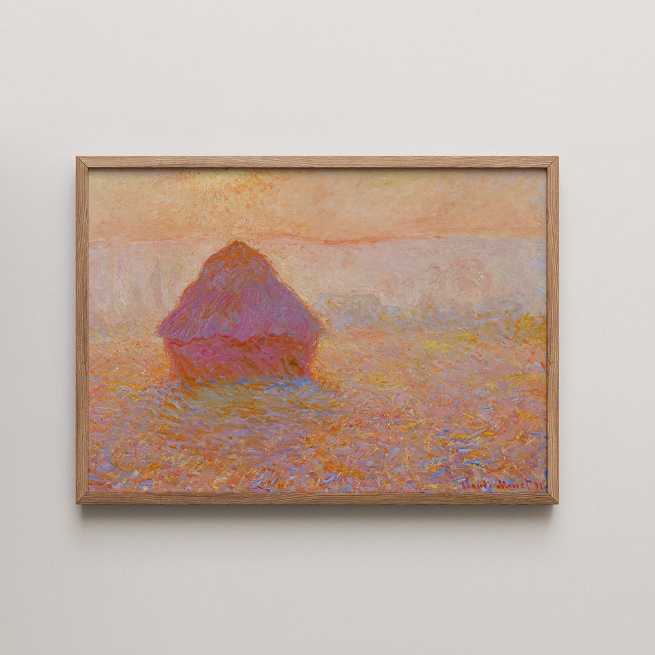 Painting of a haystack at sunset with warm pink and orange hues, framed in light wood.