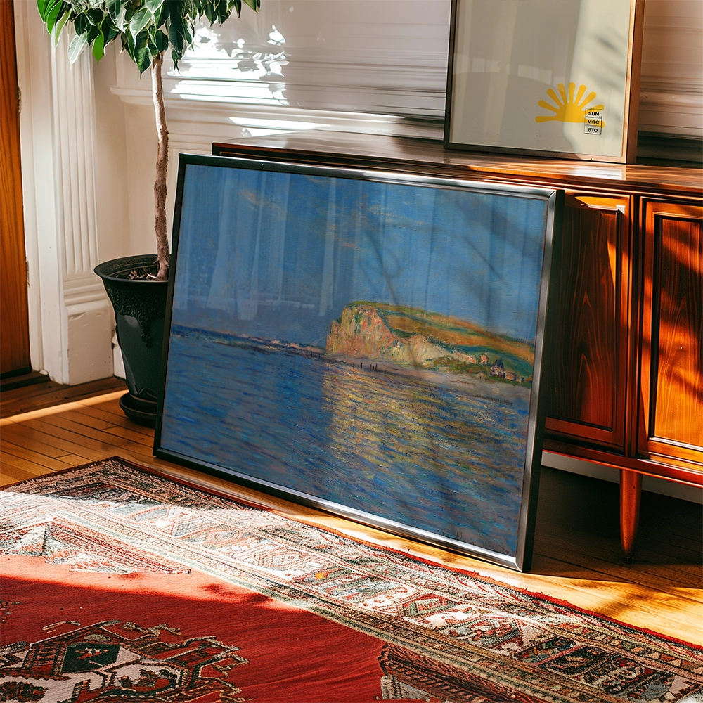Framed painting of a coastal landscape with a blue sky and reflections on water, leaning against a wooden cabinet with a potted plant nearby.