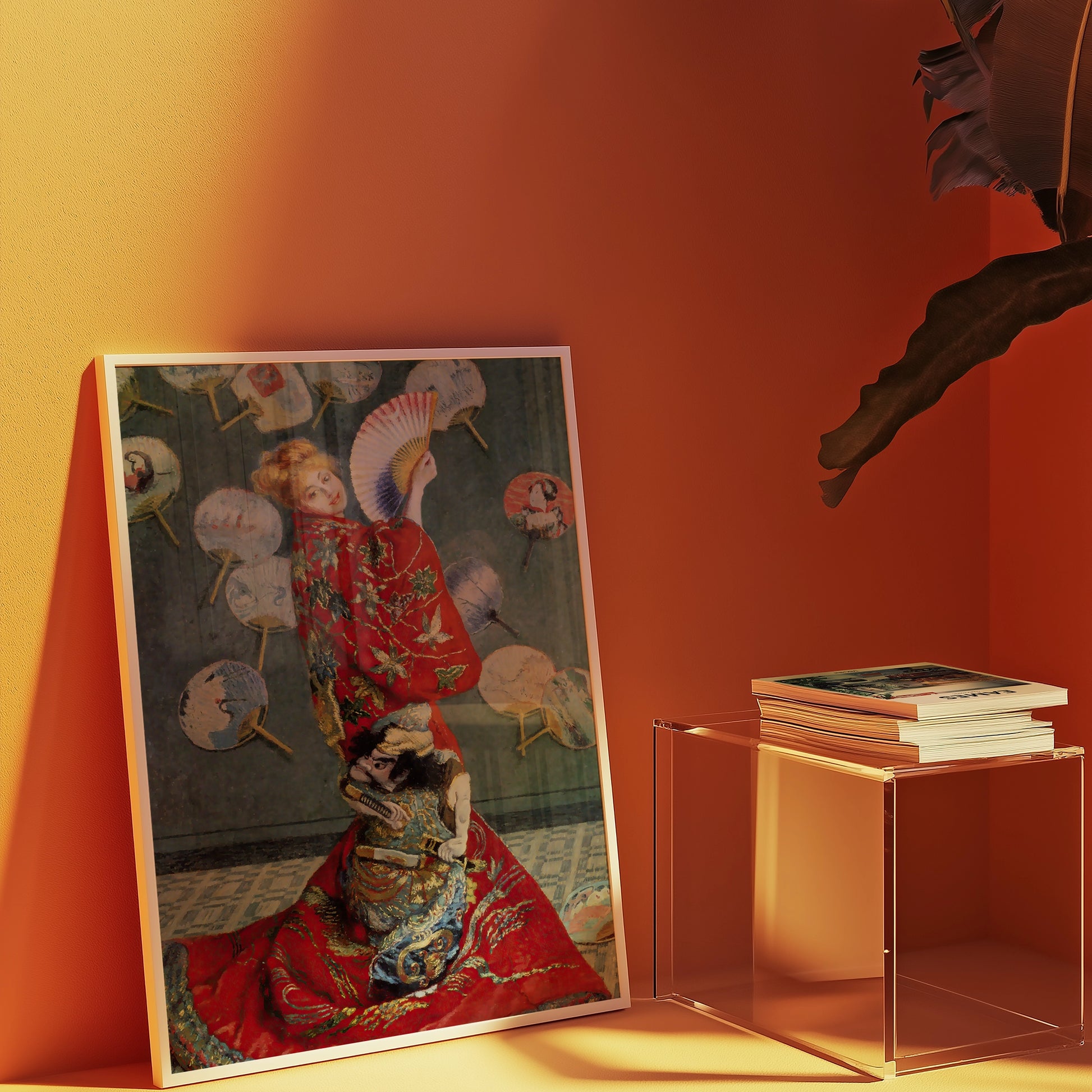 A framed painting of a woman in a red kimono holding a fan, surrounded by decorative fans, placed against an orange wall next to a clear acrylic table with stacked books.