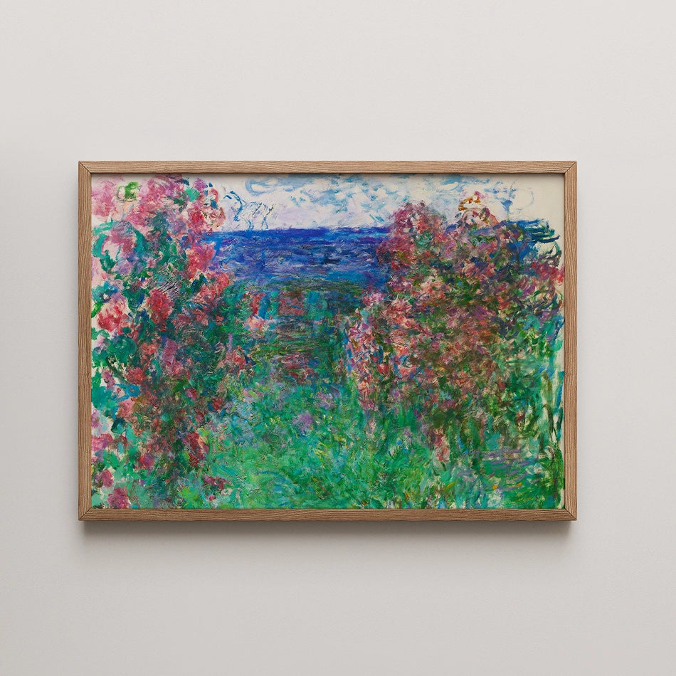 A vibrant painting featuring lush greenery and colorful flowers with a serene blue ocean in the background, framed in natural wood.