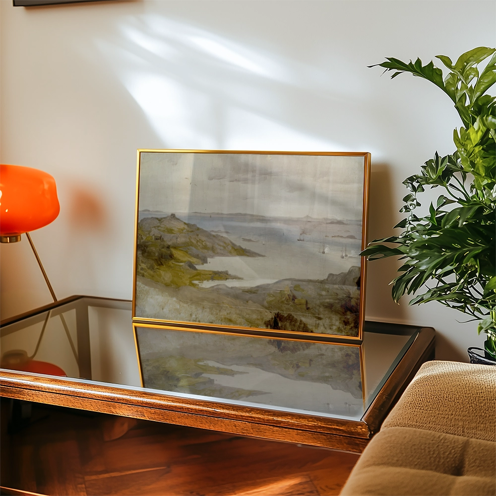 Framed watercolor landscape painting displayed on a wooden table, with a vibrant orange lamp and a green plant in the background.