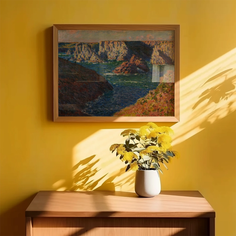 Framed landscape painting depicting a river and cliffs, displayed on a yellow wall above a wooden table with a white vase of yellow flowers.
