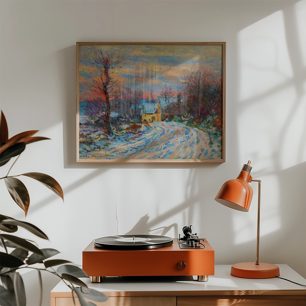 Painting of a snowy landscape with a yellow house and trees, framed and hung above a vintage record player and orange desk lamp.