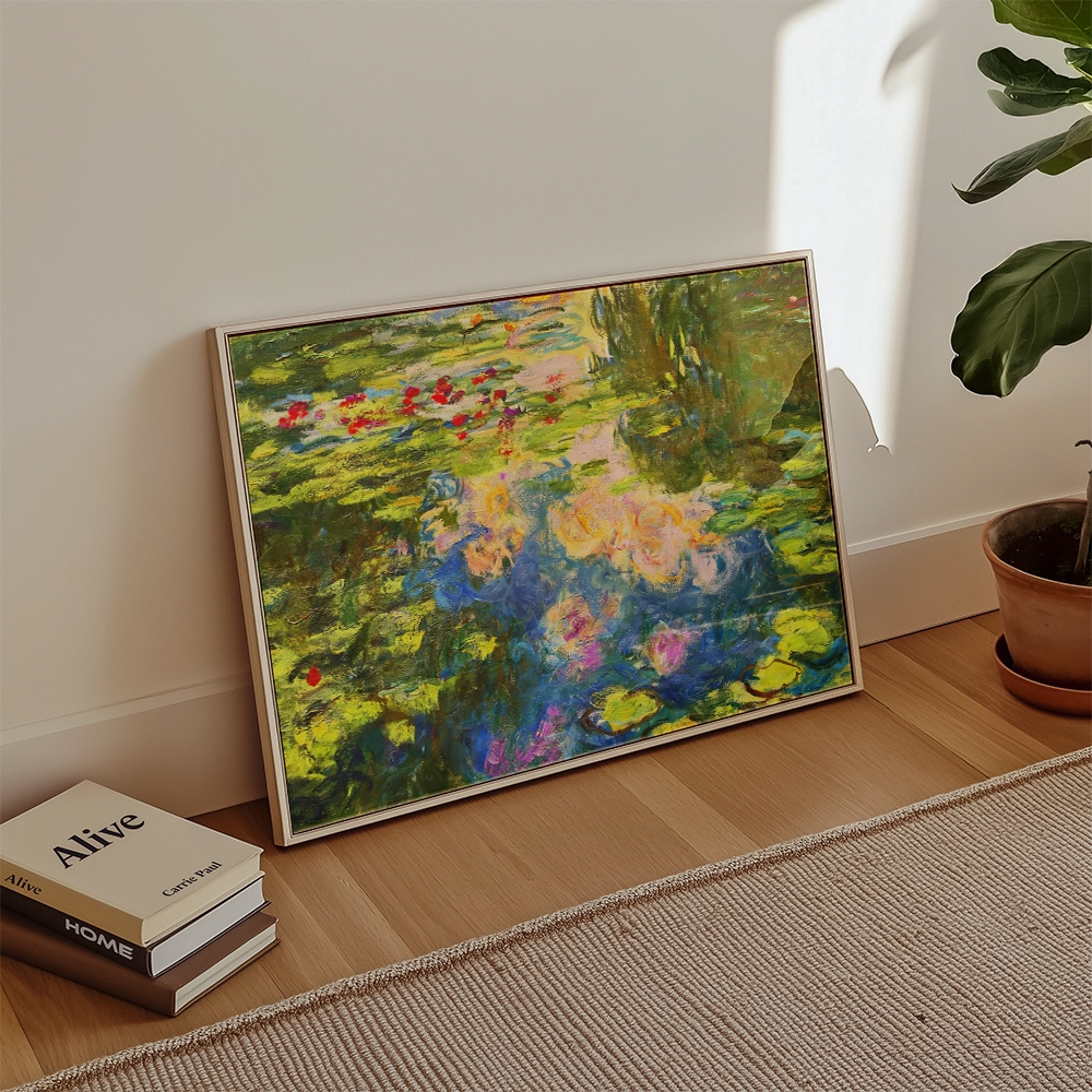 Framed painting of a vibrant water lily pond with colorful flowers, displayed on a wooden floor beside books and a plant.