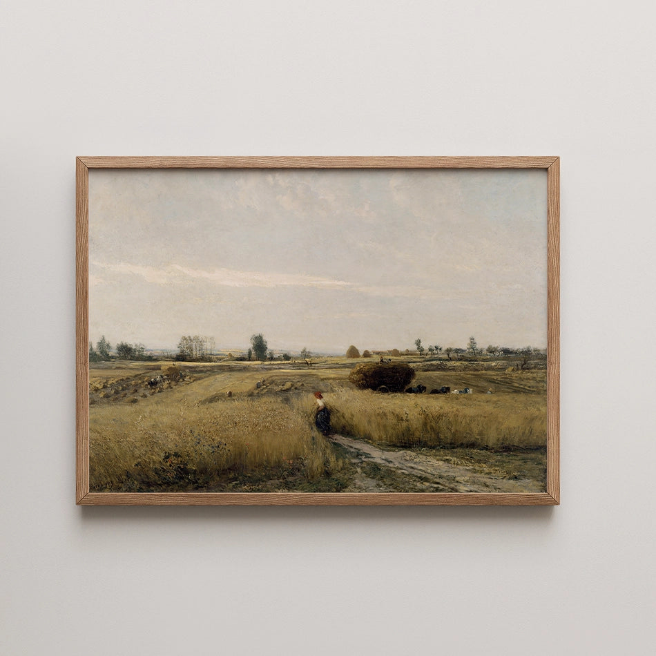 Framed landscape painting depicting a serene agricultural scene with a figure in a field of golden grass under a cloudy sky.