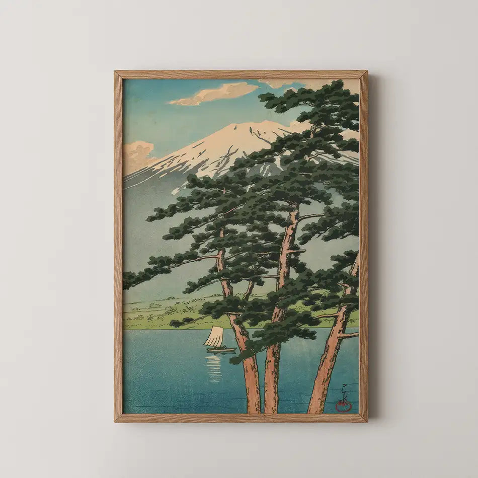 Framed painting of Mount Fuji with pine trees in the foreground and a sailboat on a calm lake, set against a blue sky with clouds.