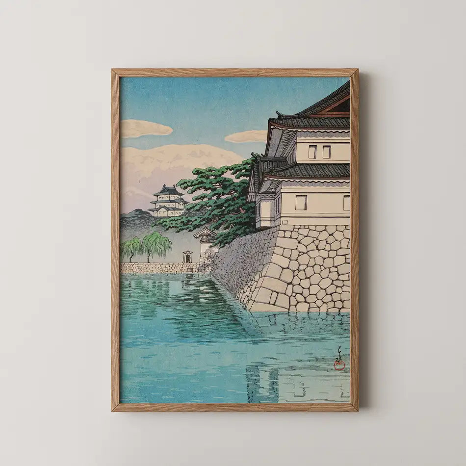 Framed painting of a serene landscape featuring traditional Japanese architecture beside a tranquil waterway with greenery and mountains in the background.