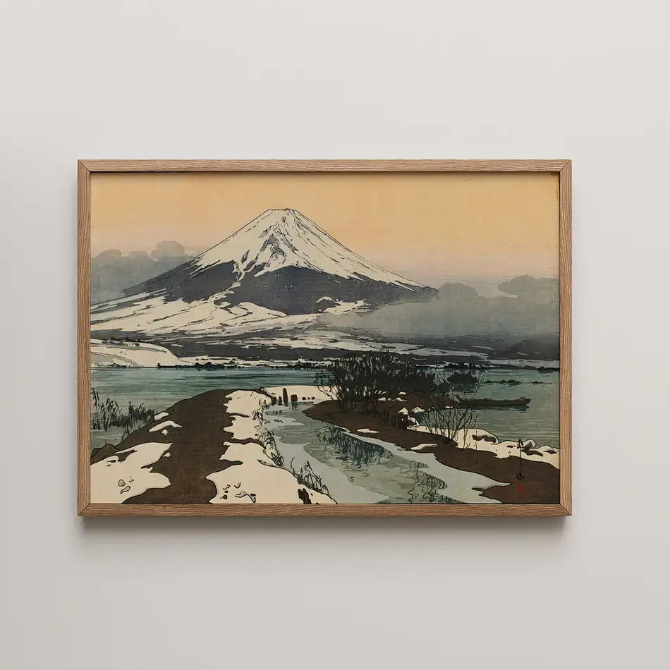 Framed painting of Mount Fuji with a winding river and snow-covered landscape under a soft orange sky.