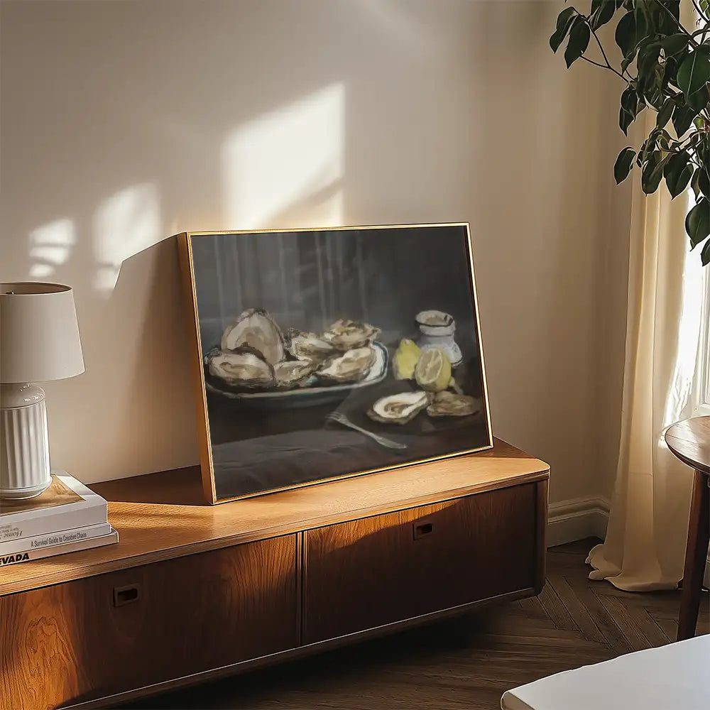 Painting of oysters on a platter with lemon and a small dish, framed and displayed on a wooden surface in a softly lit room.