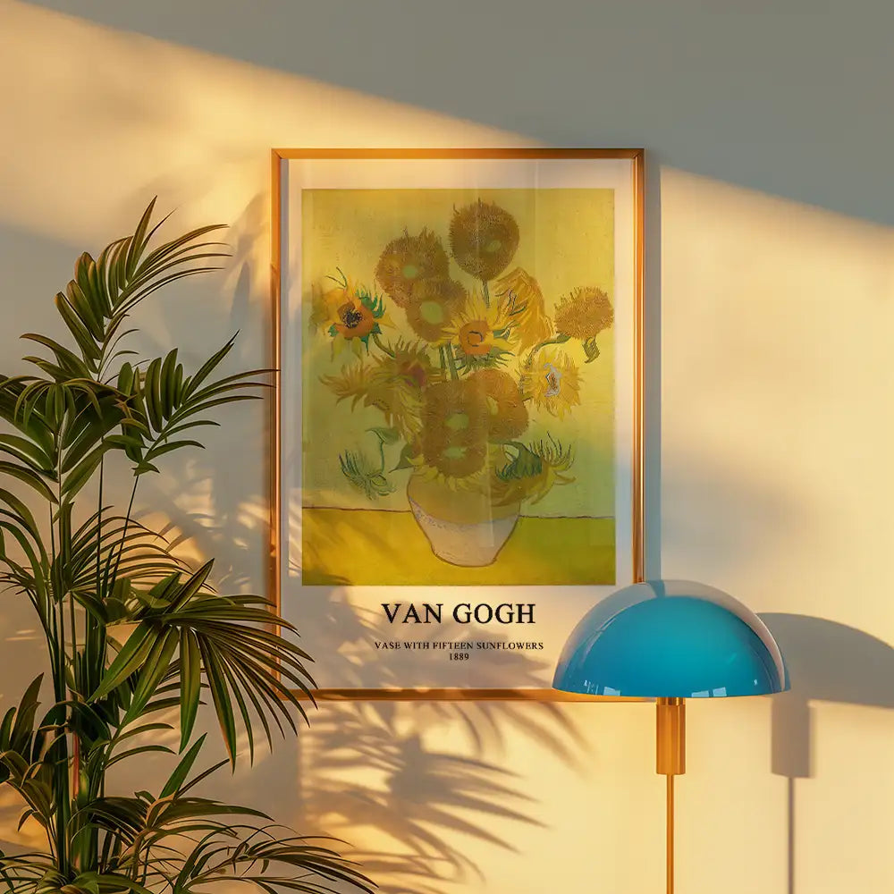 Framed poster of Van Gogh's "Vase with Fifteen Sunflowers" from 1889, displayed on a wall with a plant and a blue lamp.