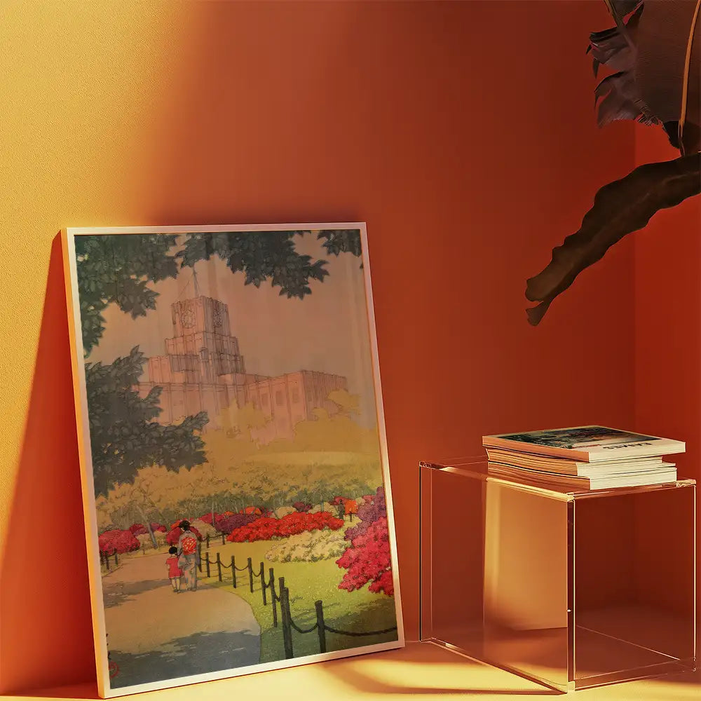 Framed painting featuring a colorful garden scene with two figures walking along a path, displayed against an orange wall beside a clear acrylic side table with stacked books.