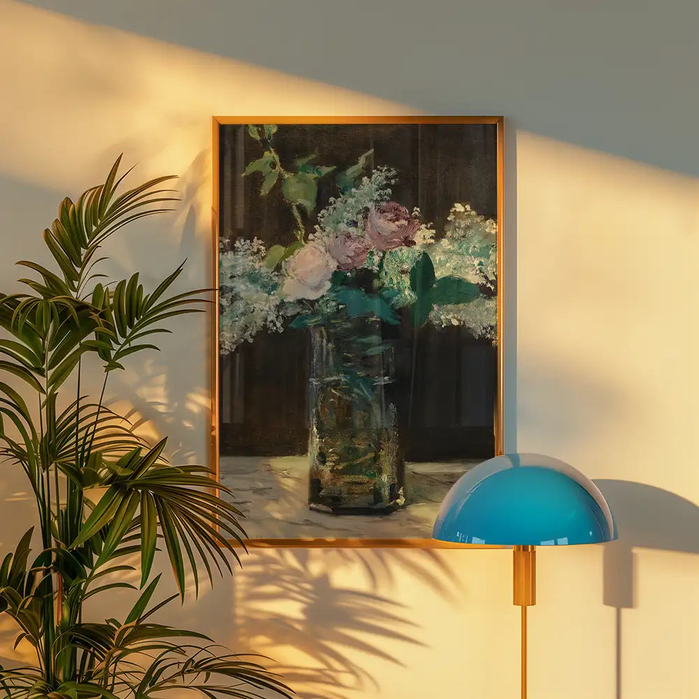 Floral painting in a glass vase framed in gold, displayed on a wall beside a green plant and a blue lamp.