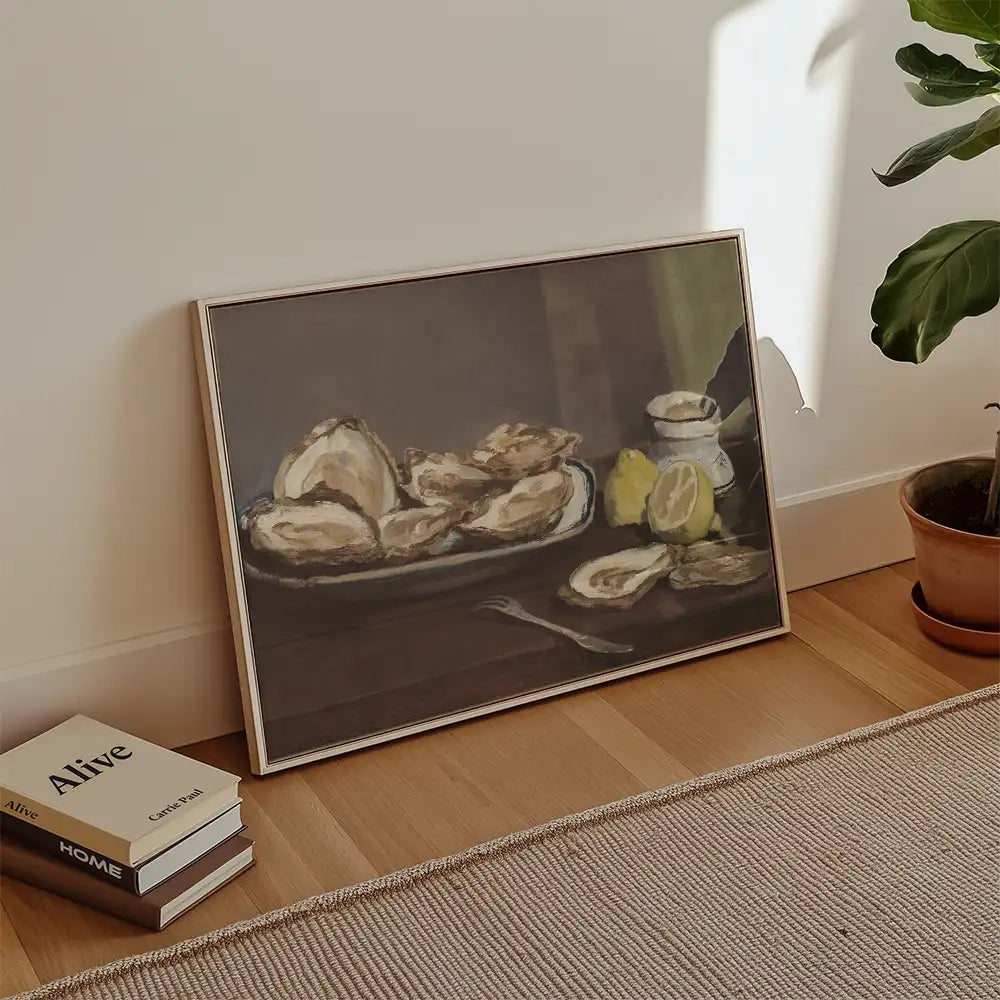 Painting of oysters on a platter with a lemon and a small jar, leaning against a wall in a bright room with plants and books nearby.