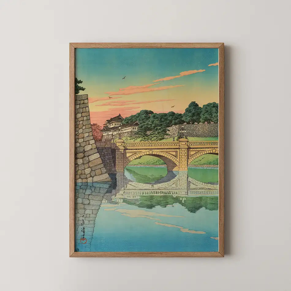 Framed painting of a scenic bridge with colorful sunset reflections over water and green trees in the background.