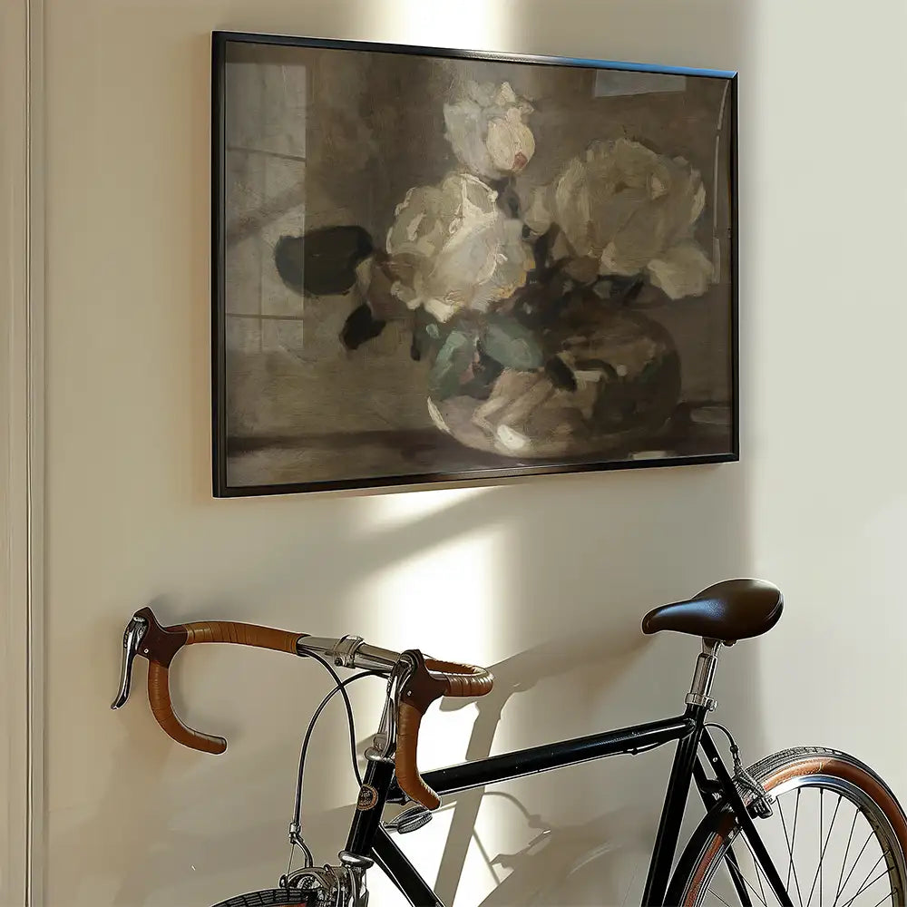 Painting of white roses in a vase framed on a wall, with a vintage bicycle nearby.