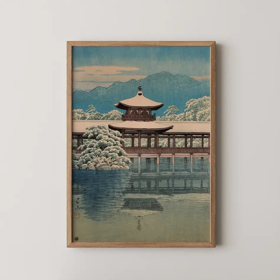 Framed painting of a traditional Asian pavilion surrounded by snow-covered trees, reflecting in still water, with mountains in the background and a pastel sky.