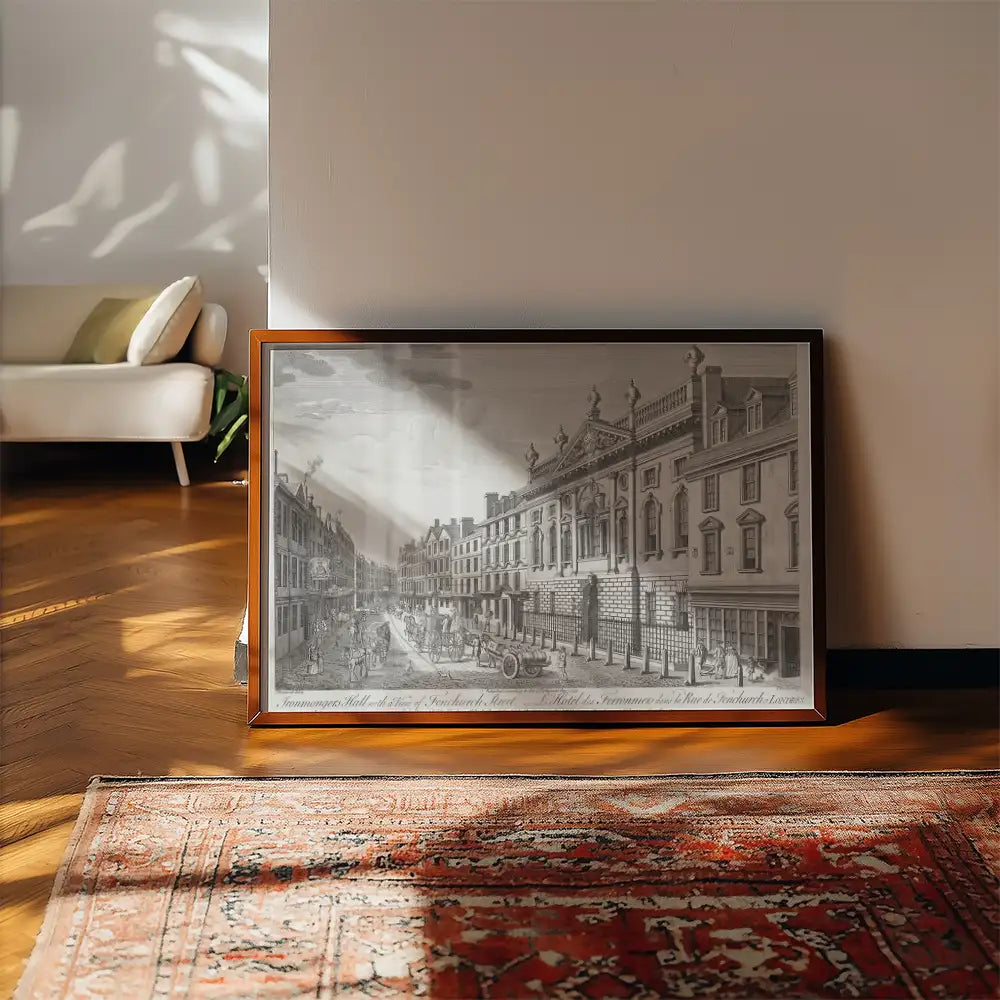 Framed black and white vintage cityscape painting propped against a wall on a wooden floor with a decorative rug nearby.