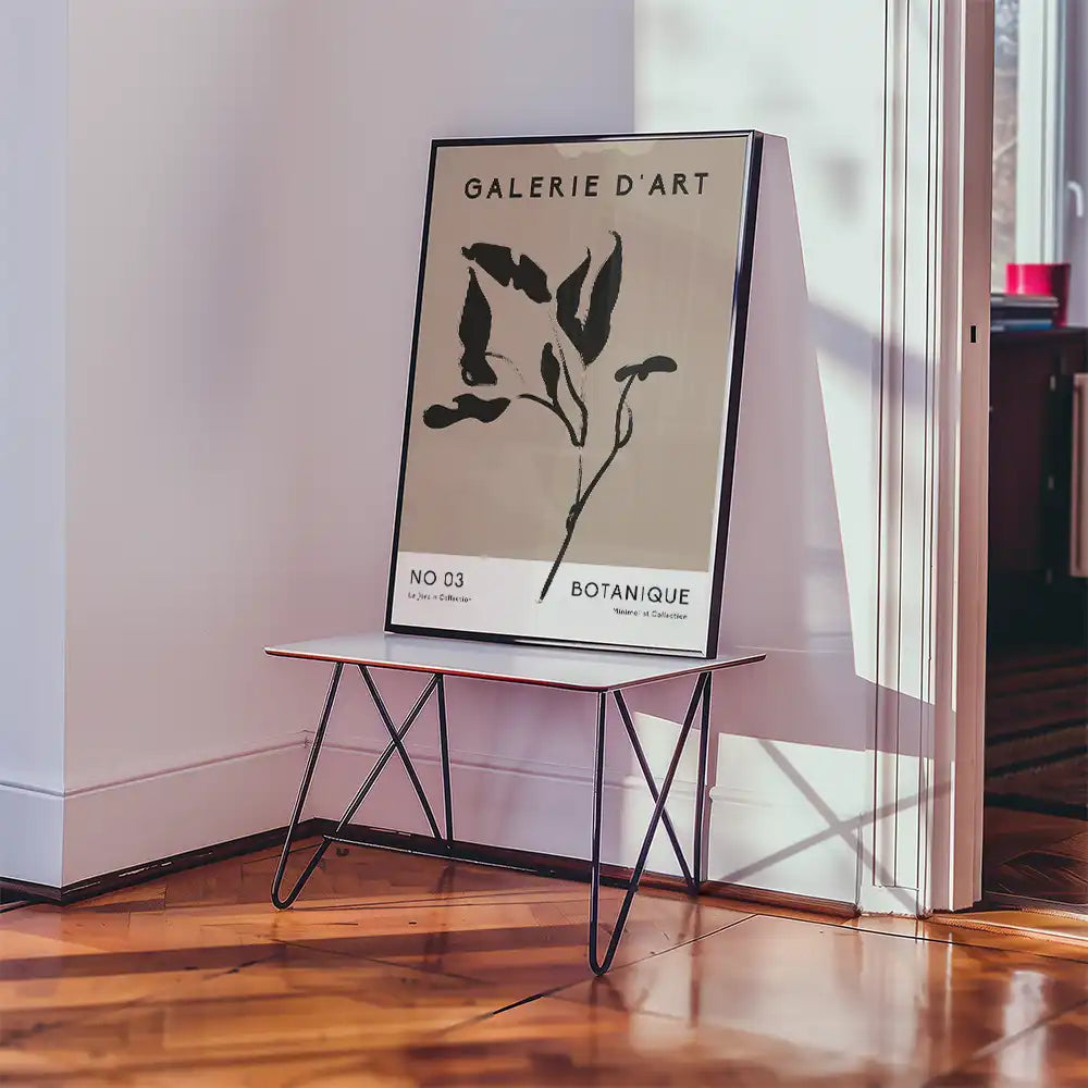 Modern botanical art poster in black and white displayed on a minimalistic table in a stylish interior setting.
