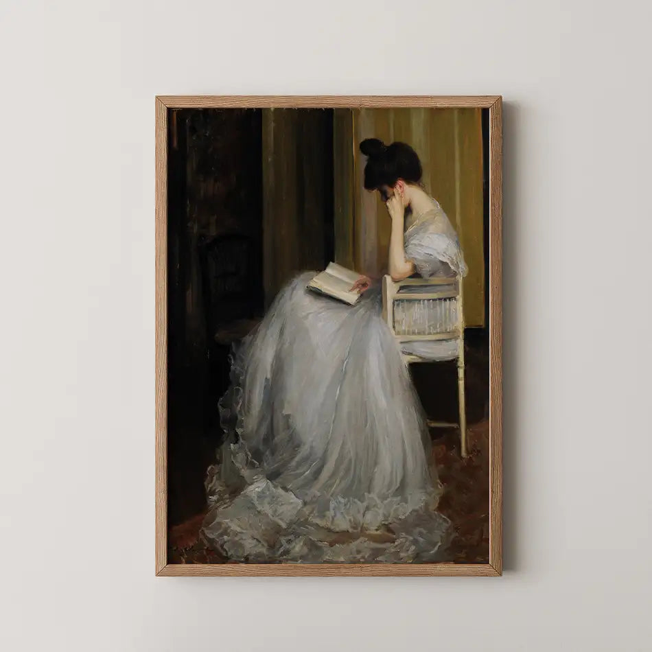 Elegant painting of a woman in a gray dress sitting on a chair and reading a book, framed in a wooden border.