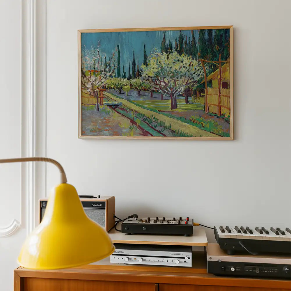 Painting of a vibrant landscape with trees and a pathway, framed and displayed on a wall above a vintage audio setup and a yellow lamp.